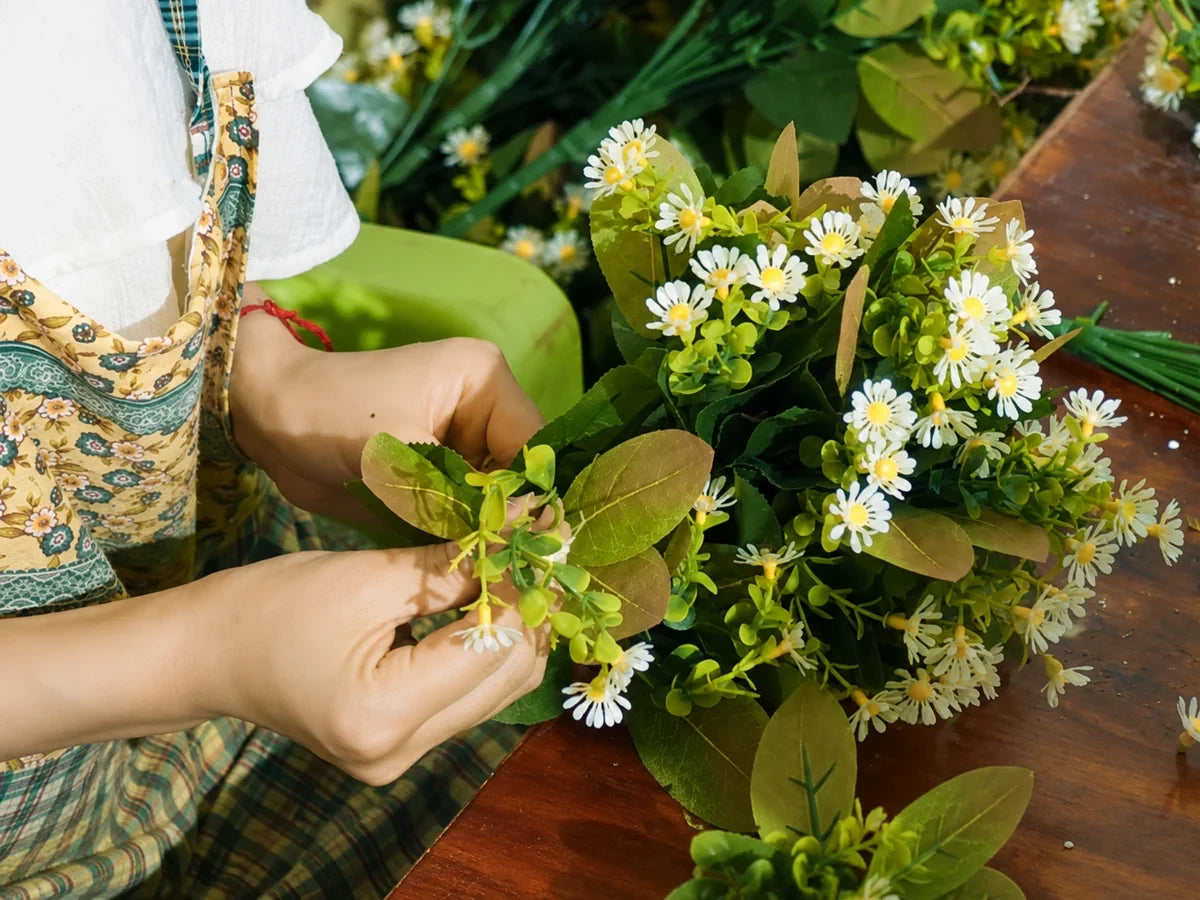 Hands working with small artificial flowers and foliage