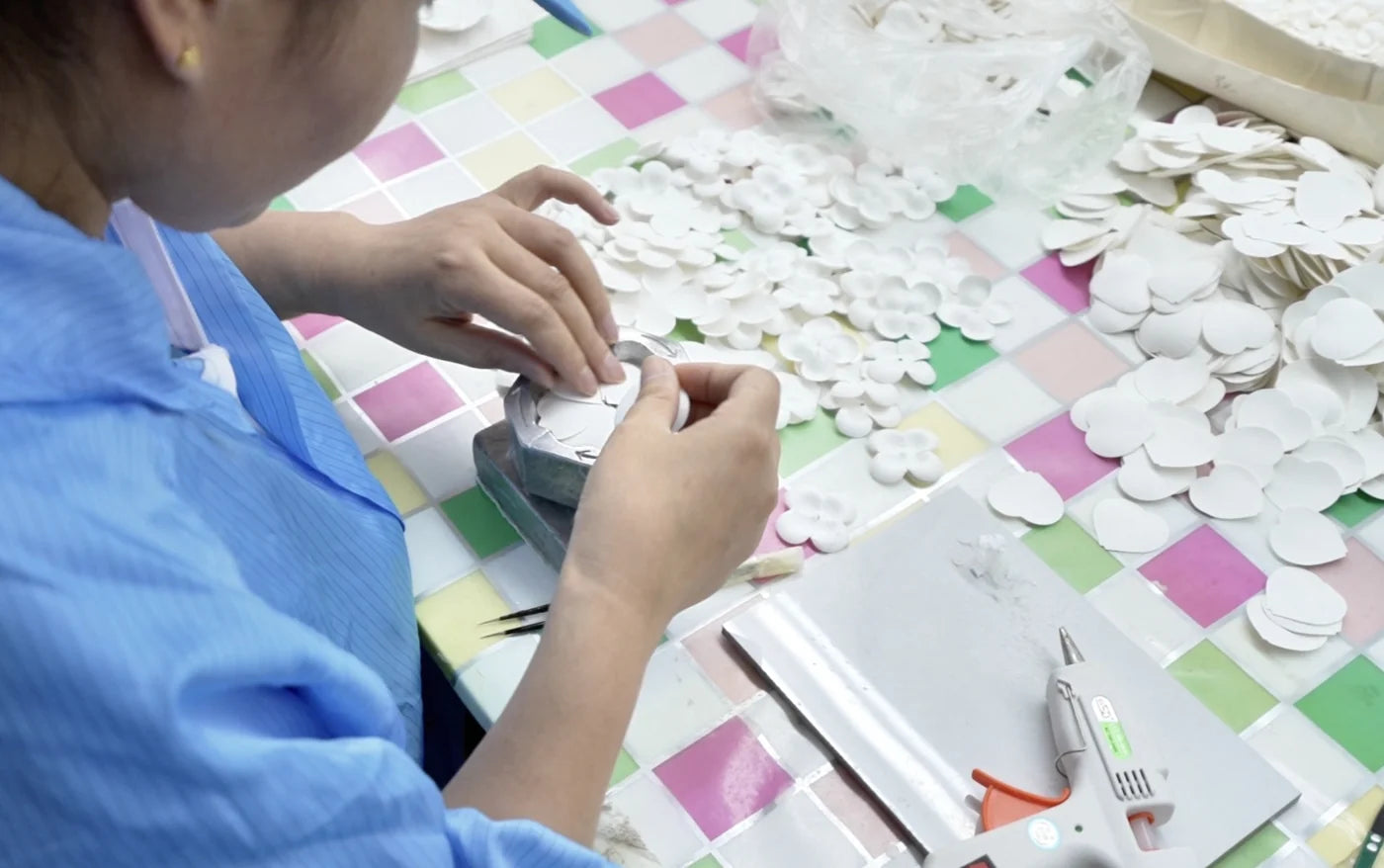 Industry reference: hands preparing flower components at a worktable