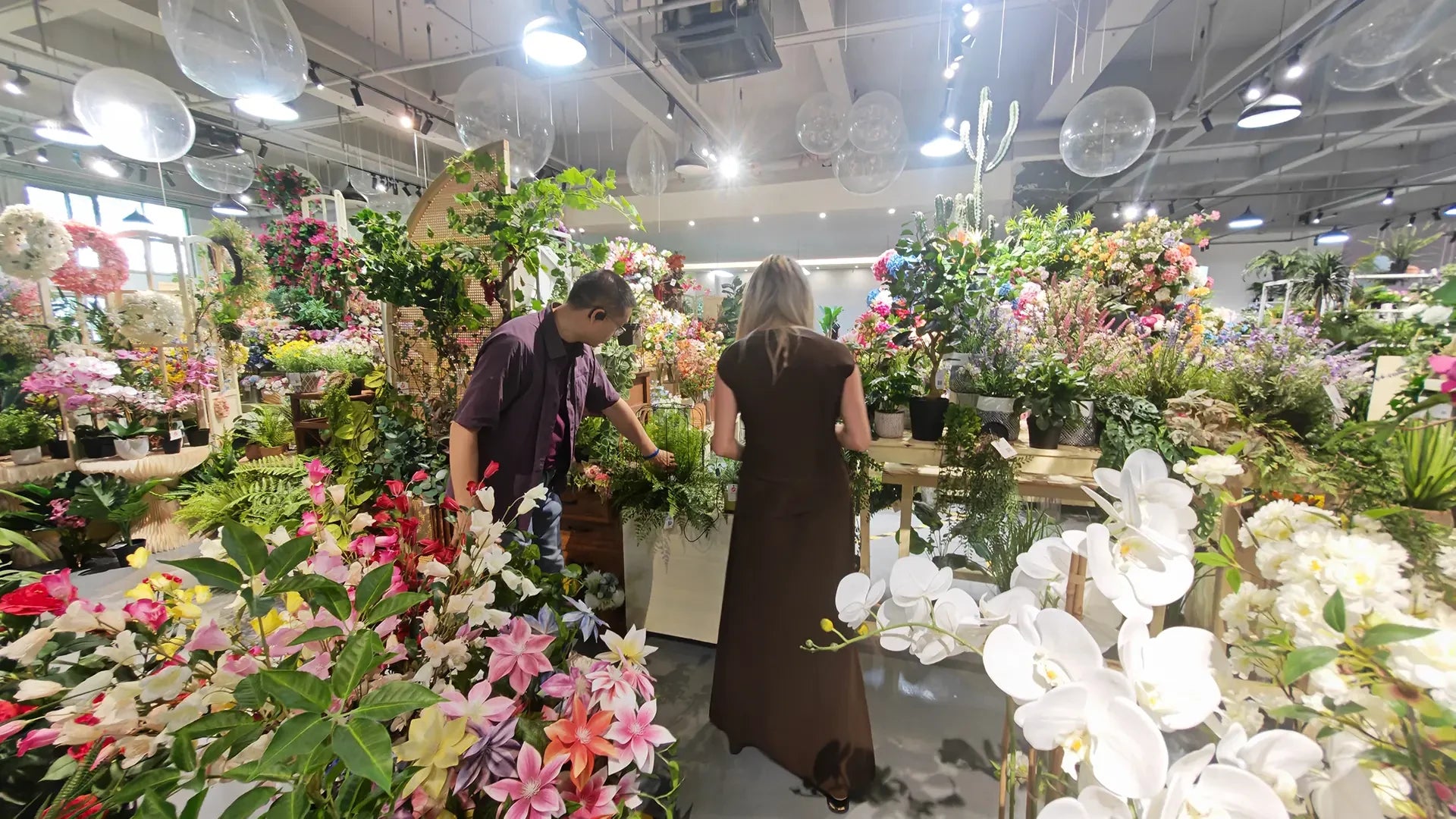 Dos personas revisando productos en una sala de exposición de flores artificiales