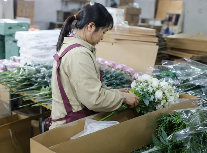 Industry reference: a worker arranging artificial flower stems for packing